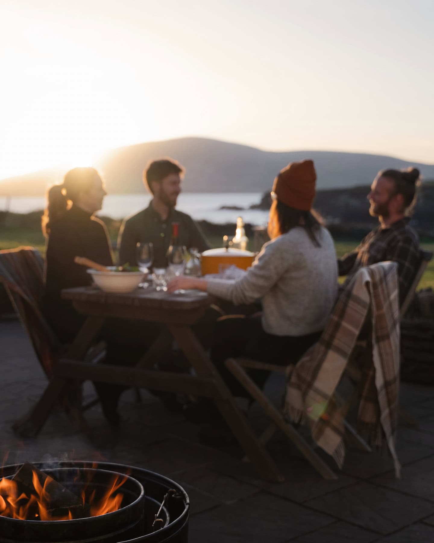 sanctuary-cottages-pipers-cottage-exterior-06 Guests enjoying a relaxed outdoor dinner at Sanctuary Cottages with views over Ventry Bay at sunset, reflecting the property's peaceful setting and amazing experience.
