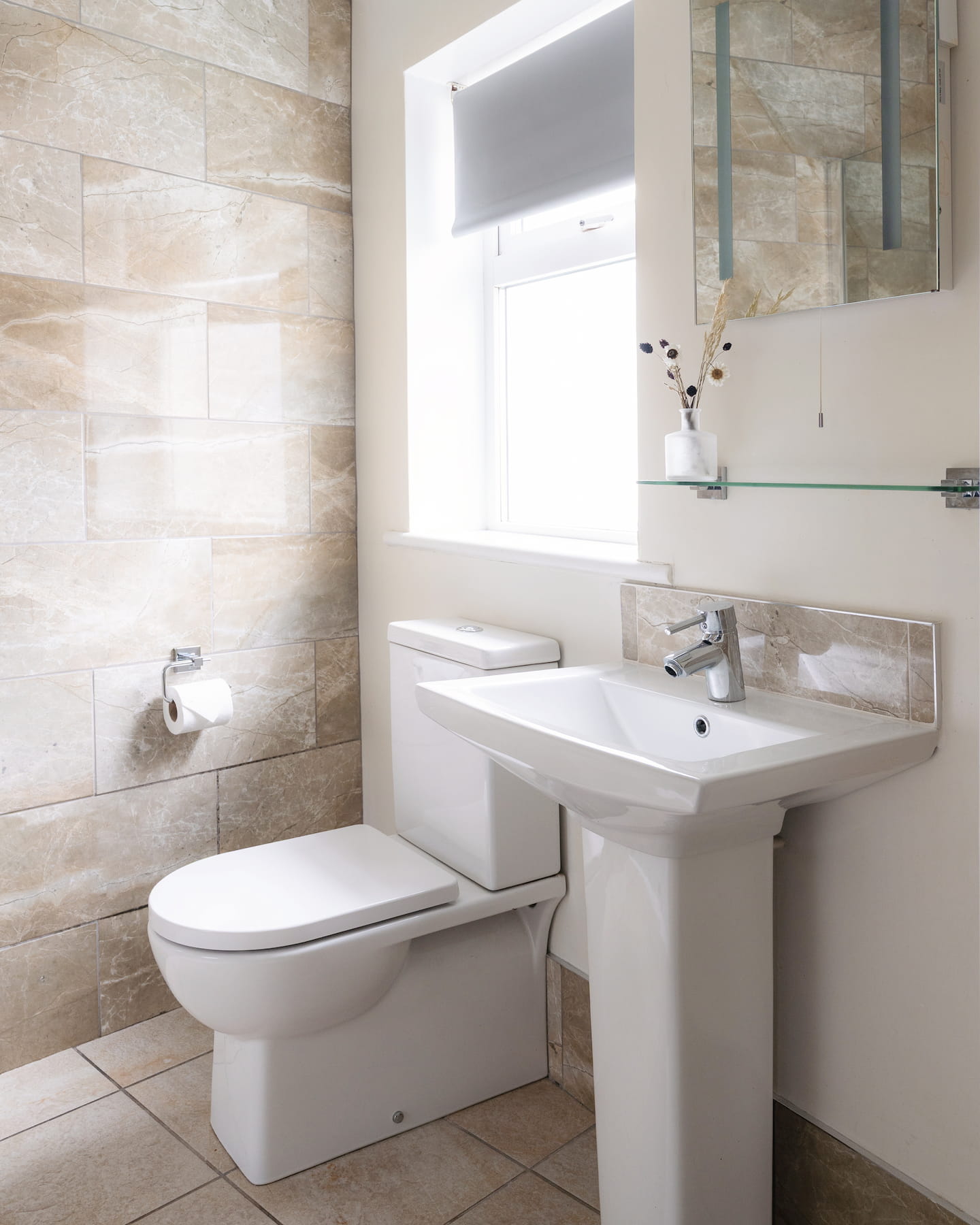 Spa like bathroom with white toilet and basin, naturally lit by a window.